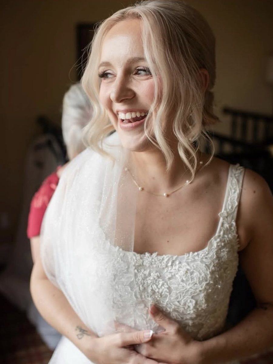 Smiling bride with soft blonde waves and a sheer veil